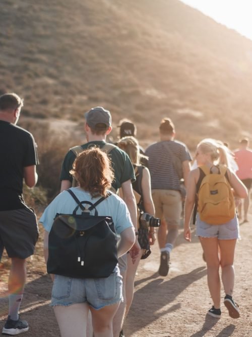 people walking on dirt road near mountain during daytime