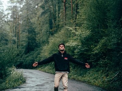 man in black long sleeve shirt and brown pants running on gray pathway between green trees